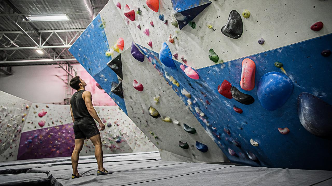 Boulderista che atterra su un materasso da bouldering in palestra