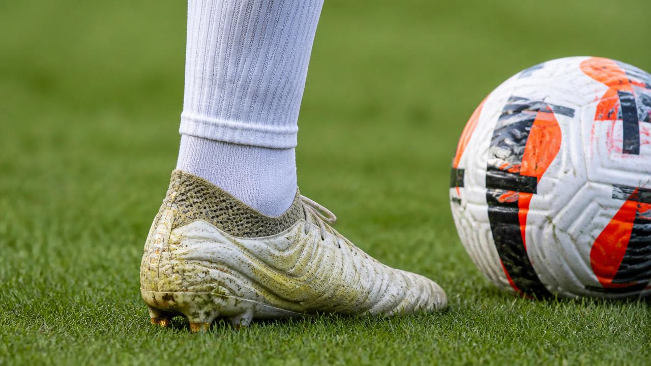 Primo piano della caviglia di un calciatore in scarpa da calcio durante il tiro