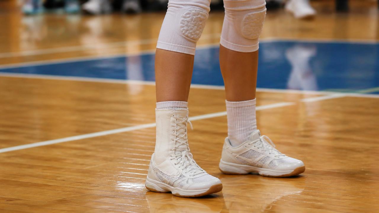Gambe di una pallavolista su campo indoor con cavigliera sportiva a lacci indossata sopra il calzino